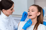 Dentist in blue gloves examining patient's teeth in professional dental office setting.