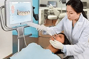 Dentist examining patient's teeth in modern dental office treatment room.
