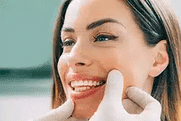 Woman smiling while touching her face, demonstrating dental health and oral care confidence.