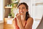 Smiling woman in dental office setting with shelves and plants in background
