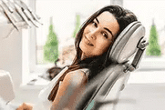 Woman relaxing in dental chair wearing headphones at modern dentistry office.