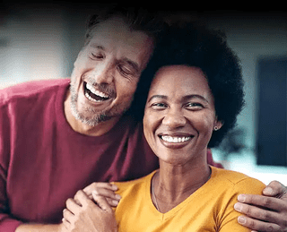Happy couple smiling together in bright indoor setting, representing dental care and family wellness.