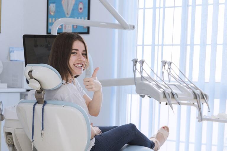 Smiling patient giving thumbs up while sitting in dental chair at Winchester practice.