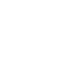 Dentist in white coat and mask treating patient in dental chair with overhead light.