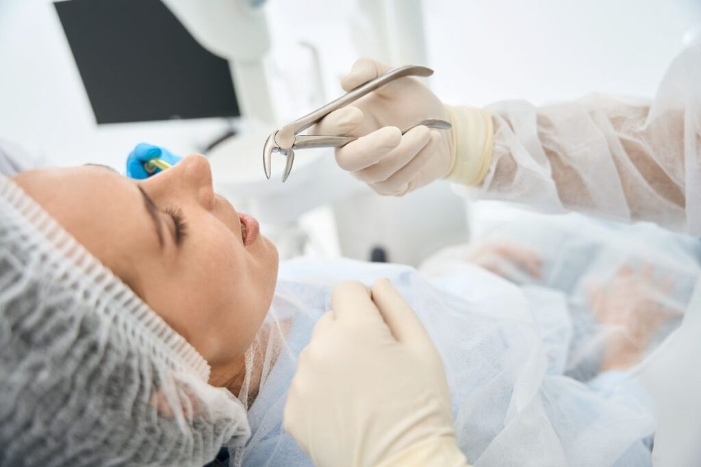 Dentist performing tooth extraction on patient under anesthesia in Winchester dental office.