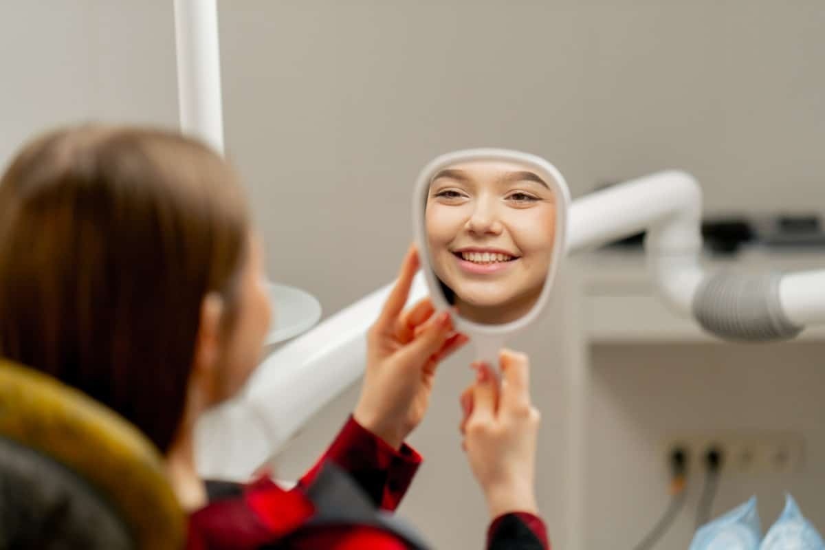 Young patient smiling in dental mirror during cosmetic dental treatment at Winchester practice.