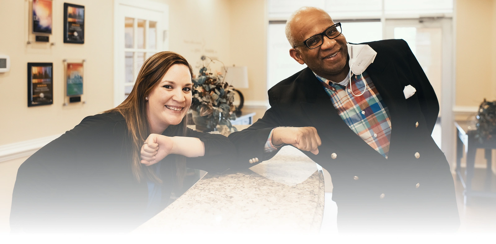 Smiling dental team members sitting together at a reception desk.
